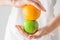 Young Caucasian woman in white shirt holding in hands raw green organic apple orange. Stomach gut health dietary fiber