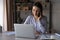 Young Caucasian woman work on laptop talk on smartphone