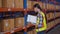 Young caucasian woman worker checking with scanning barcode and writing record document on clipboard.