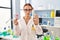 Young caucasian woman working at scientist laboratory holding toxic label with open hand doing stop sign with serious and