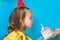 Young celebrating girl blowing candle on a piece of cake on blue background. Copy space