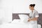 Young chambermaid with pillow in hotel room.