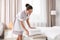 Young chambermaid putting clean towels on bed bench