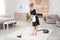 Young chambermaid removing dirt from carpet with vacuum cleaner