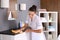 Young chambermaid wiping dust from furniture with rag