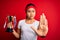 Young champion asian girl winning trophy cup standing over isolated red background with open hand doing stop sign with serious and