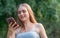 Young charismatic beautiful european girl with long blond hair holding a phone in her hands and smiling, female portrait