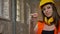 Young charming attractive women in helmet, earphones and glasses looking, pointing in camera, smiling, female builder