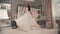 Young charming brunette dressed in white dress poses for wedding shooting in bright interior.