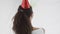 Young charming brunette in red party hat joyfully plays with two baloons sending them flying through the air. 360 degree