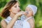 Young charming caring mother gives daughter drink