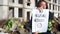 Young charming Caucasian woman in builder vest standing at construction site with placard protesting against