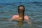 Young charming girl bathes in the sea and dries her hair in the water, rear view