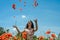 Young charming girl in a chamomile poppy field tosses petals of poppies on a bright sunny day