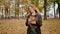 Young charming girl in a coat throws colorful autumn leaves, posing and laughing in the camera. Enjoying the autumn