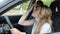Young charming girl straightens her hair while driving a car