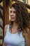 Young charming leggy girl with curly hair in a white shirt and red shorts sitting on the wooden stairs near the fortress in Lviv