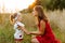 Young charming mother crouched near her little daughter in the field