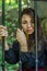 Young charming teenager girl with long dark hair sitting behind bars in a prison in the old castle fortress serving a sentence for