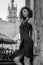 Young charming woman with long curly hair, strolling among the old town of Lviv architecture in black dress