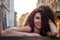 Young charming woman with long curly hair, strolling among the old town of Lviv architecture in black dress