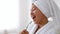 Young cheerful asian woman with towel on head wearing bathrobe singing into toothbrush, dancing at bathroom