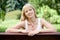 Young cheerful blond woman on the bench in summer