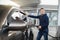 Young cheerful Caucasian man in casual outfit, refueling his modern luxury car at fuel station, smiling to camera