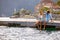 Young cheerful couple holding hands up in air, enjoying and celebrating summer holiday on wooden jetty by water. Tourism,