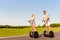 Young cheerful couple in love driving segways and smiling in park