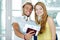 Young cheerful couple with travel bags holding tickets with passports