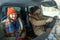 Young cheerful couple in warm winterwear looking through front window of car