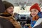 Young cheerful couple in warm winterwear looking at you with smiles inside car