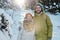 Young cheerful couple in winterwear enjoying winter day in the forest