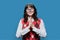 Young cheerful female pleading holding her palms together, on blue background