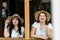 Young and cheerful females couple have fun and laugh together in friendship - trendy girls with straw hat at the window enjoy