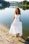 Young cheerful girl bride walk barefoot the sunny coast of the river