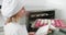 Young cheerful girl confectioner in the pastry workshop, holding the baking tray with colorful macarons shells after