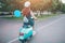 Young cheerful girl driving scooter in in city. Portrait of a young and stylish woman with a moped