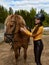 Young cheerful girl equestrian hugging her favorite red horse. Vertical image