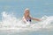 Young cheerful girl teenager blonde European appearance makes splashes of water with her hands in the sea