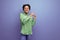 young cheerful positive hispanic brunette lady dressed in a green stylish blouse smiling on the background with copy