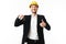 Young cheerful realtor in yellow safety helmet happily showing thumb up while looking in camera with keys of new flat in