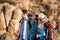 Young cheerful travelers with backpacks smiling, embracing, walking in canyon.
