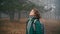 A young cheerful woman enjoys the fresh air while walking in the misty forest