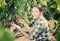 Young cheerful woman picking ripe grapes on vineyard