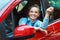 Young cheerful woman sitting in a car with keys in hand