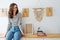 Young cheerful woman sitting on a shelf in a corridor, next wall lamps