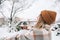 Young cheerful woman tosses a handful of snow up, having fun enjoying wintertime