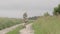 Young cheerful woman walks on a field road to the house.